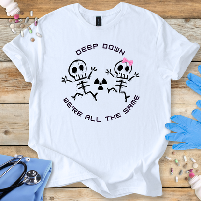 White t-shirt with radiology skeleton design and 'Deep down we are all the same' text on a wooden surface with medical supplies.