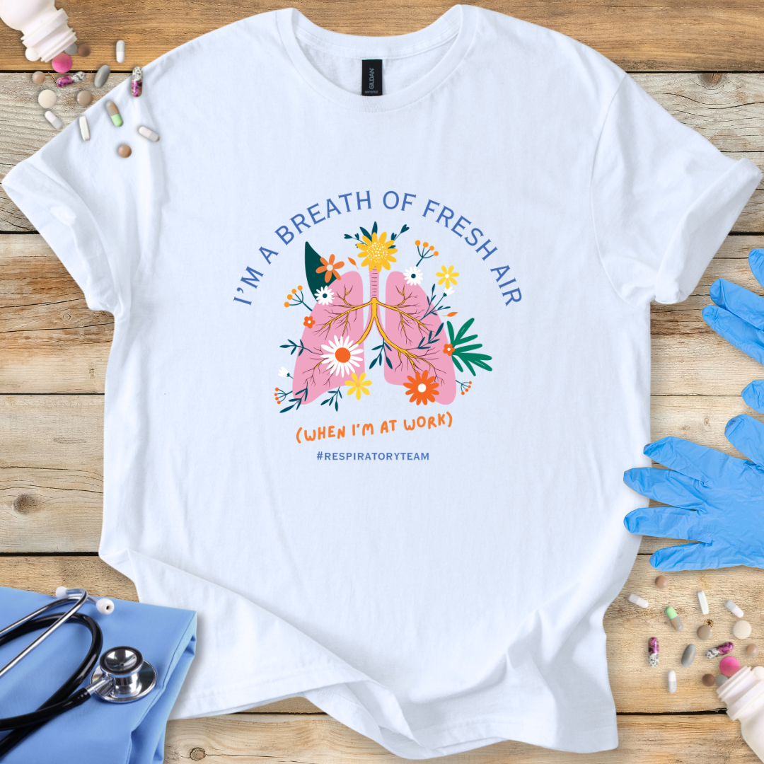 White t-shirt with a colorful respiratory therapy graphic and 'I'm a breath of fresh air' text on a wooden surface with medical supplies.